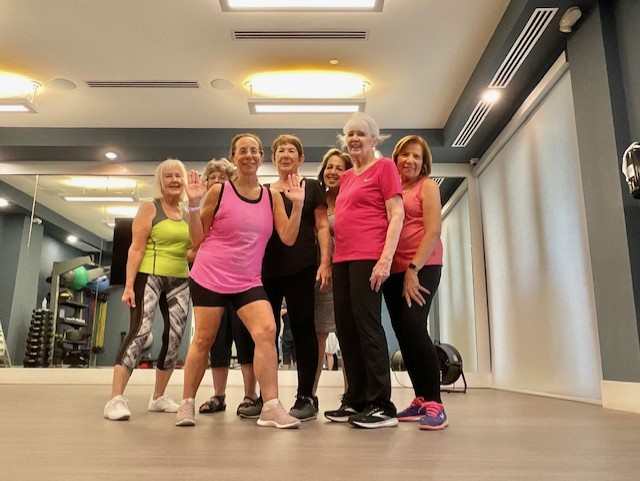 Linda with her Zumba class smiling and posing in a sunlit studio