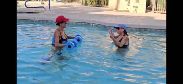 Linda leading an aqua fitness class in the pool with noodles