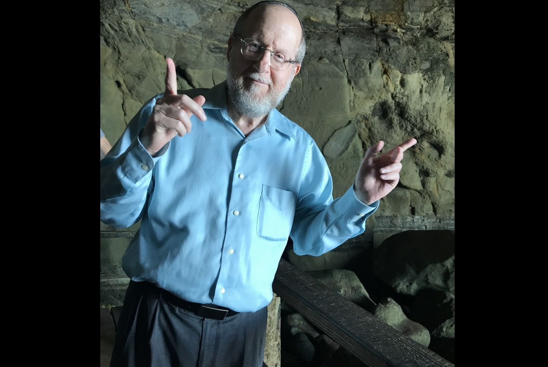 Naftali Schwartz in a blue shirt inside a historic stone cave