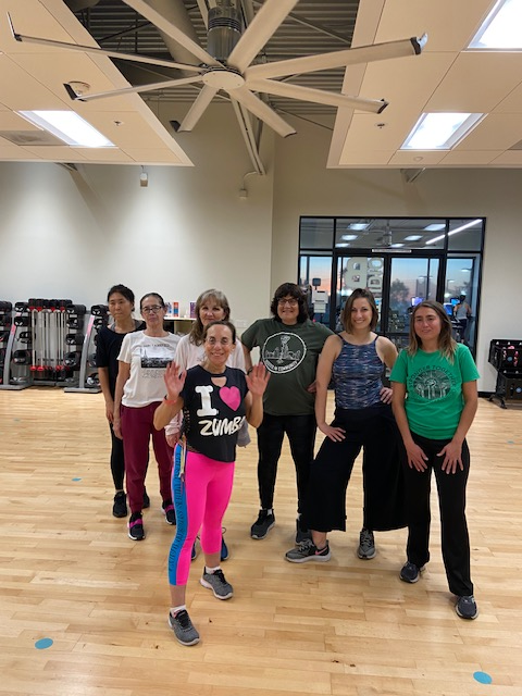 Linda with her Zumba class smiling and posing together in a bright studio