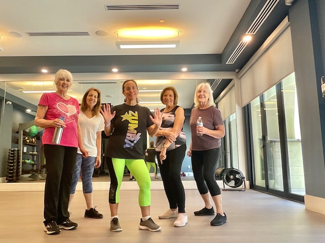 Linda dancing in a Zumba shirt with a group of women in the studio